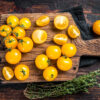 Yellow cherry tomato sliced on a wooden cutting board. Dark wood Pomodoro Ciliegino Avorio semi