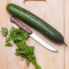 cucumber and parsley on wooden cutting board with knife, top view Cetriolo Marketer semi