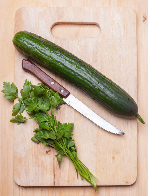 cucumber and parsley on wooden cutting board with knife, top view Cetriolo Marketer semi