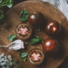 top view of black prince tomatoes, basil leaves and garlic on cutting board with gauze Pomodoro Ciliegia Brown Berry semi